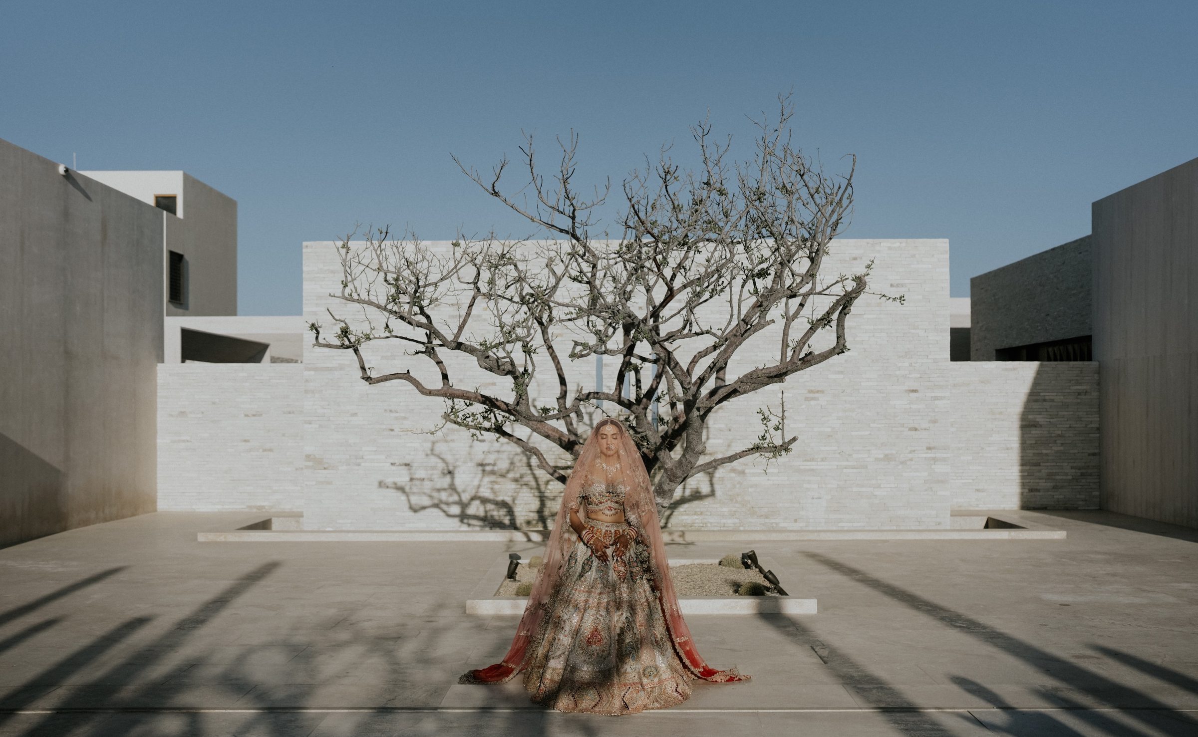 Bride standing in a sunlit stone courtyard